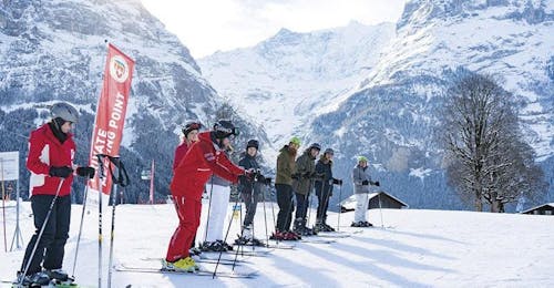 Skilessen voor kinderen (6-15 jaar) voor beginners met Swiss Ski School Grindelwald Een groep skiërs wacht op de piste tijdens hun kinderskilessen voor halfgevorderden bij de Grindelwald-skischool.
