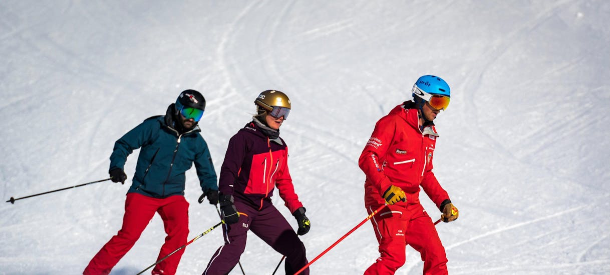 Two skiers follow their instructor during their adult ski lessons for beginners with the Grindelwald Swiss Ski School.