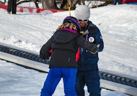 A ski instructor from the Swiss Ski School Grindelwald assists a student with her first attempts during a snowboarding lessons for kids and adults for beginners. 