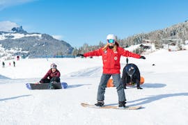 Eine Snowboardlehrerin der Schweizer Skischule Grindelwald macht ihren Schülern während dem Snowboardkurs für Kinder rund Erwachsene für fortgeschrittene Snowboarder Übungen vor.
