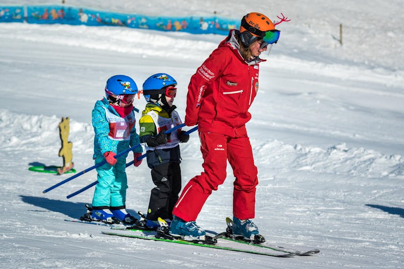 A ski instructor from the Swiss Ski School Grindelwald pulls two small children behind him during a private kids ski lesson for all levels.
