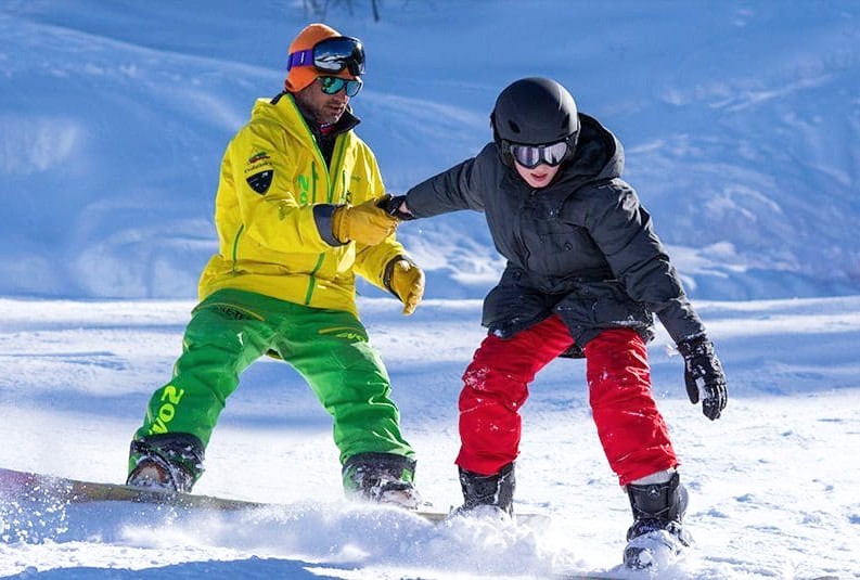 An instructor of Evolution 2 Peisey Vallandry is helping a snowboarder during their Private Snowboarding Lessons.