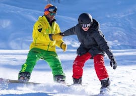 Un moniteur d'Evolution 2 Peisey Vallandry aide un snowboardeur pendant son Cours particulier de snowboard.
