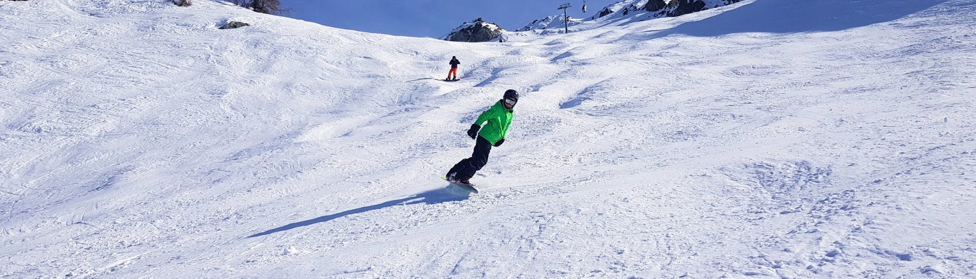 Een snowboarder rijdt een helling af tijdens hun Privé Snowboardles bij Evolution 2 Peisy Vallandry.