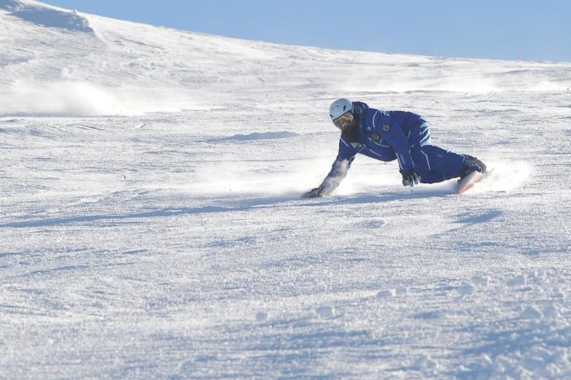 Maestro di snowboard si allena ad Andalo prima di una delle Lezioni di snowboard per bambini e adulti di tutti i livelli.