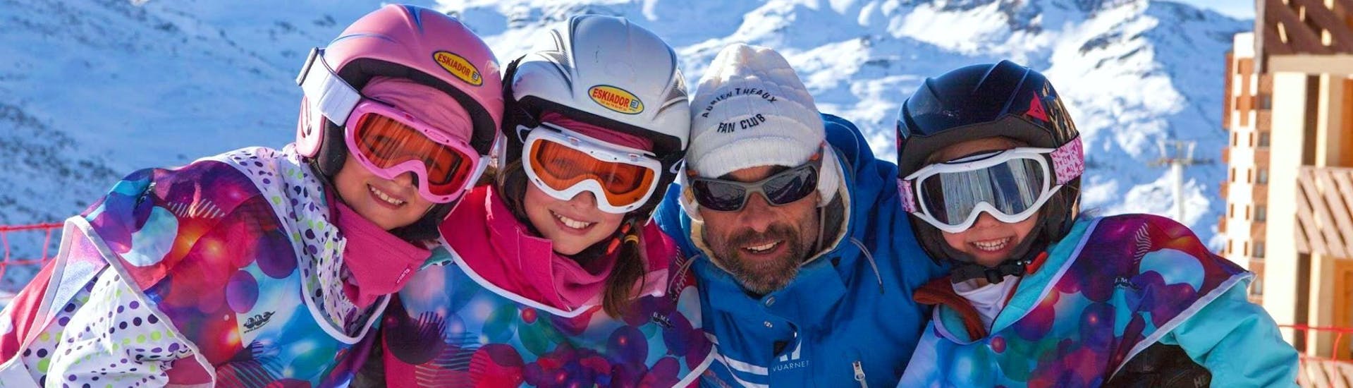 Des enfants avec leur moniteur de ski de l'école de ski Prosneige Val d'Isère prennent la pose devant un paysage de montagnes enneigées pendant leur Cours de ski Enfants + Forfait (5-13 ans) pour Débutants.