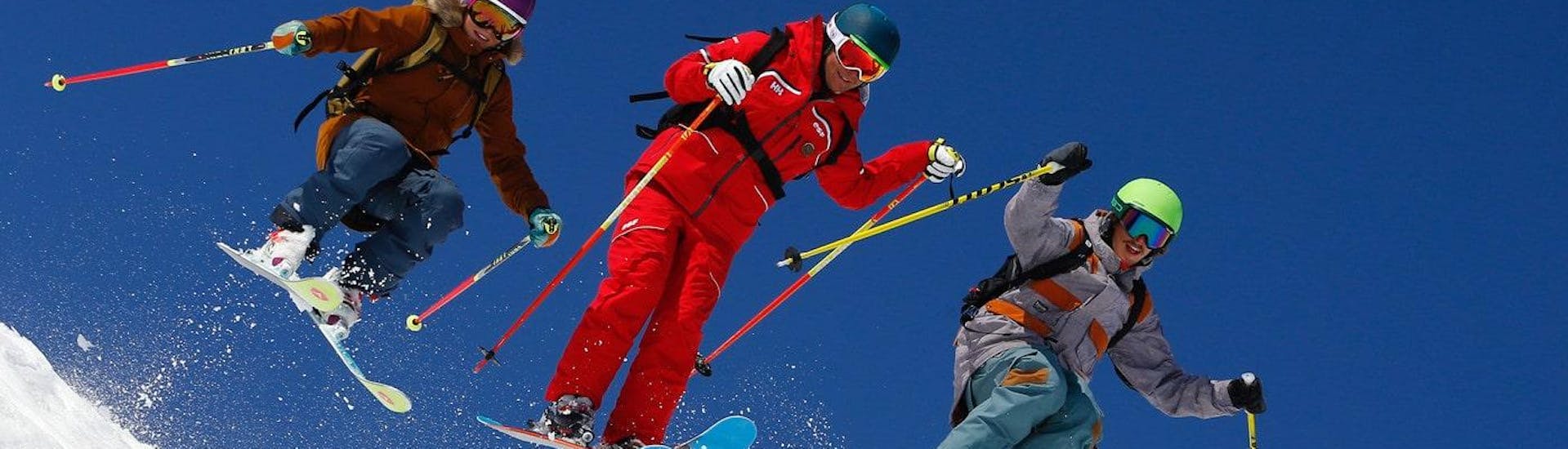 Des skieurs skient avec assurance avec leur moniteur de ski de l'école de ski ESF Alpe d'Huez pendant leur Cours de ski pour Adultes - Tous niveaux.