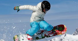 A snowboarder is doing a jump during their Snowboarding Lessons for Kids (8-12 years) - All Levels with the ski school ESF Alpe d'Huez.
