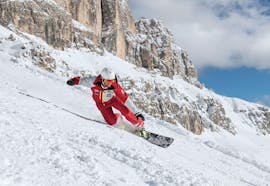 Un maestro di snowboard della Carezza Skischool scende la pista per primo durante le Lezioni di snowboard per bambini e adulti - Principianti.