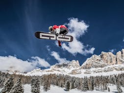 Ein Snowboarder führt einen Trick aus während dem Snowboardkurs für Kinder & Erwachsene - Fortgeschritten der Carezza Skischool.