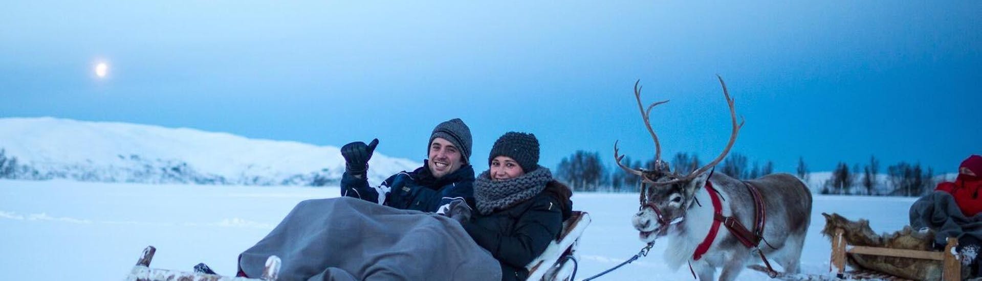 Een stel geniet van een romantische rit tijdens het Night Reindeer Sledding in Tromsø & Reindeer Feeding georganiseerd door Tromso Arctic Reindeer.
