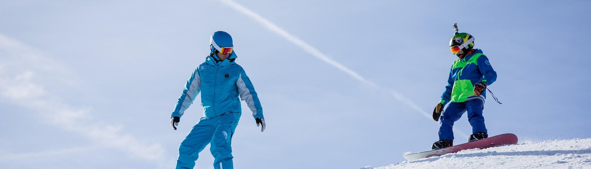 Un jeune snowboardeur suit son moniteur de snowboard de l'école de ski ESI Gliss'Émotion Super-Besse sur une piste pendant son Cours particulier de snowboard pour Enfants & Adultes.