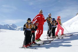 Skiers are standing around their ski instructor from the ski school ESF Chamonix ready to begin their Kids Ski Lessons "Ski Session" (5-12 years).