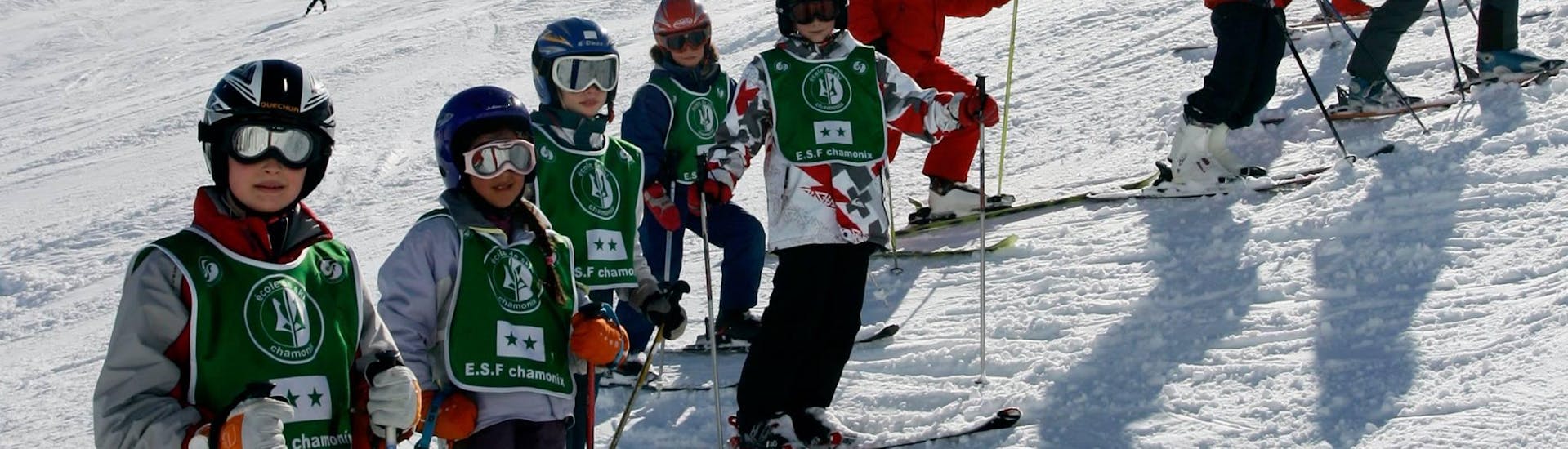 Des skieurs se tiennent au milieu de la piste en compagnie de leur moniteur de ski de l'école de ski ESF Chamonix pendant leur Cours de ski Enfants (8-12 ans) - Vacances - Avancé.