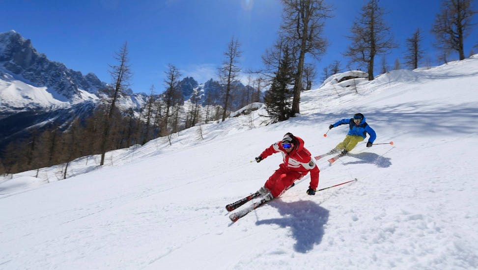 Ein Skifahrer folgt seinem Skilehrer von der ESF Chamonix auf einer verschneiten Piste während des Skikurses für Erwachsene - Alle Levels. 