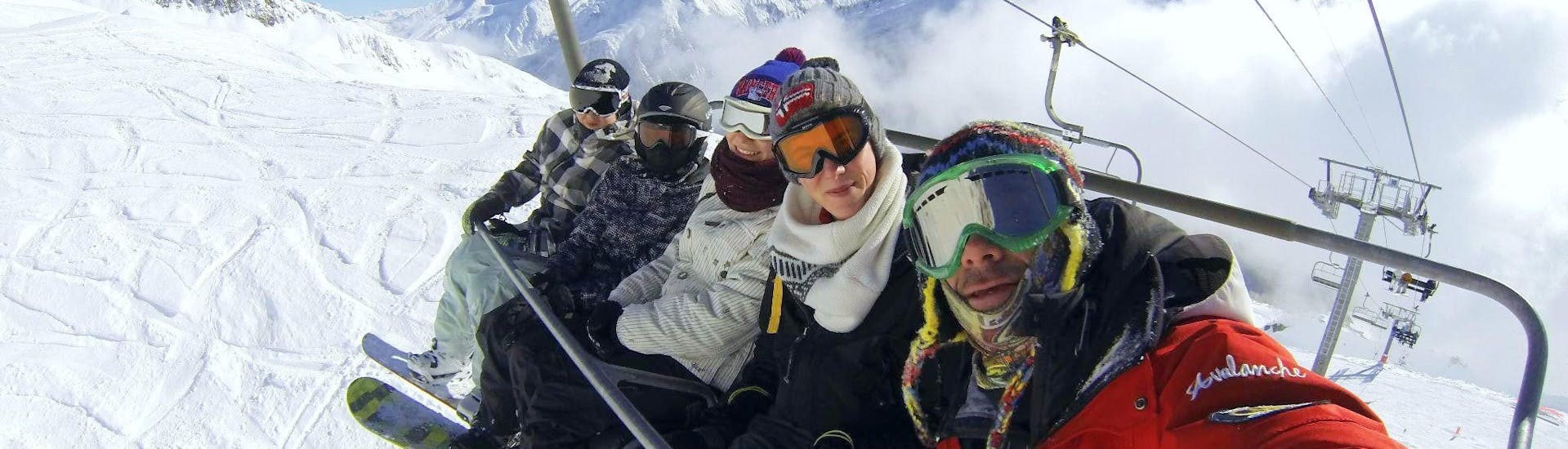 A group of snowboarders is sitting in a chairlift bringing them to the top of the mountain where they will start their Snowboarding Lessons for Adults - All Levels with the ESF Chamonix.