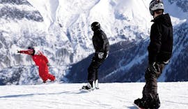 A snowboarder is following their instructor from the ski school ESF Chamonix on a snowy slope during their Snowboarding Lessons for Adults - All Levels. 