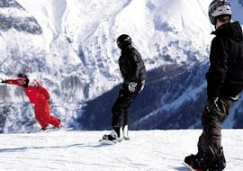 Un snowboardeur suit son moniteur de snowboard de l'école de ski ESF Chamonix le long d'une piste enneigée pendant son Cours de snowboard pour Adultes - Tous niveaux.