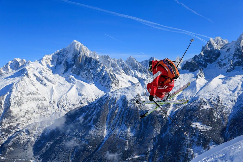Voor een berg springt een skiër terwijl hij aan het freeriden is tijdens zijn Off-Piste Skitour "Mont Blanc Ski Discovery" met de skischool ESF Chamonix.