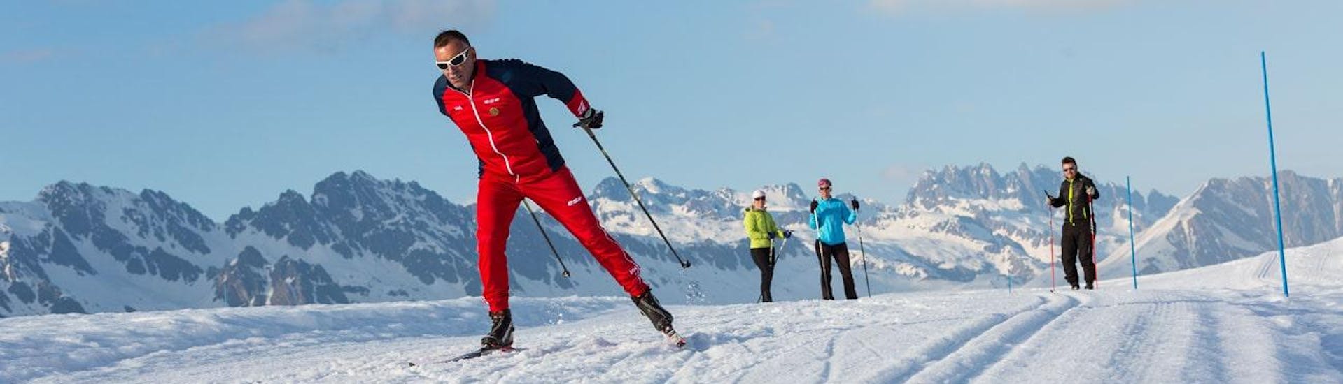Two skiers are observing their cross-country skiing instructor of the ski school ESF Chamonix during their Cross-Country Skiing Lessons for Adults - All Levels.
