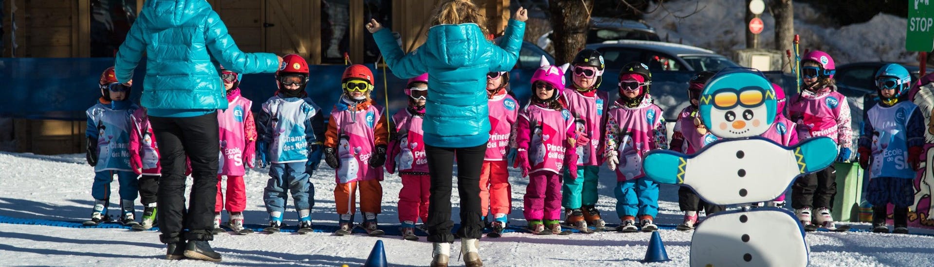 Young children are standing in line and listening to their ski instructor from the ski school ESI Dévoluy before starting their Kids Ski Lessons "Club Souris" (5-7 years).