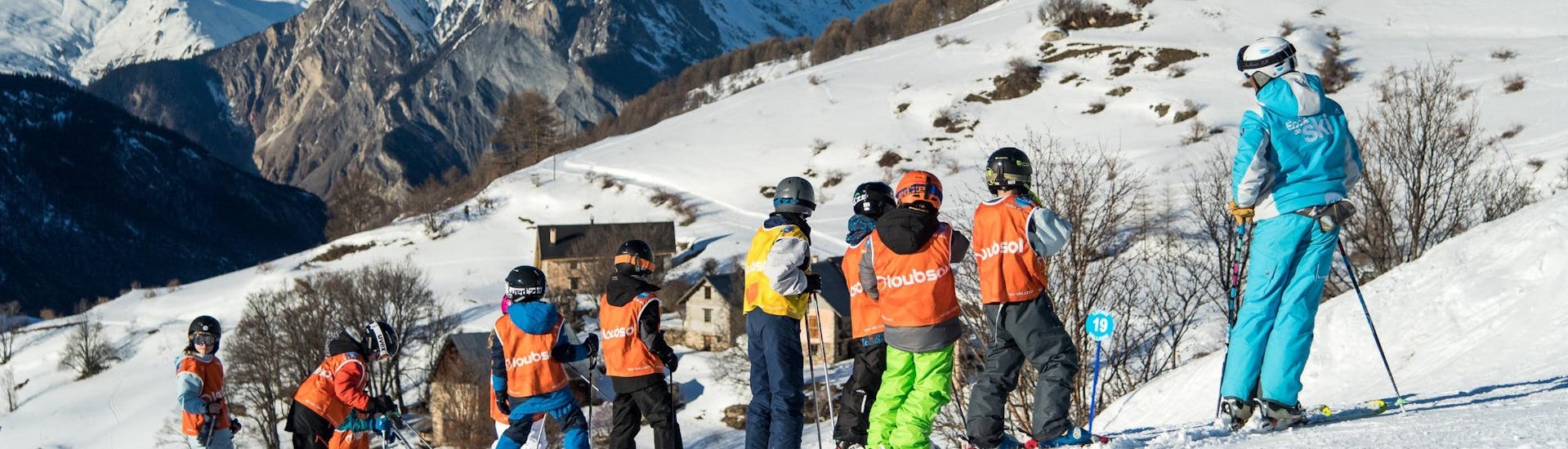 Young skiers are standing in the middle of a beautiful winter landscape during their Kids Ski Lessons (8-15 years) - All Levels with the ski school ESI Dévoluy.