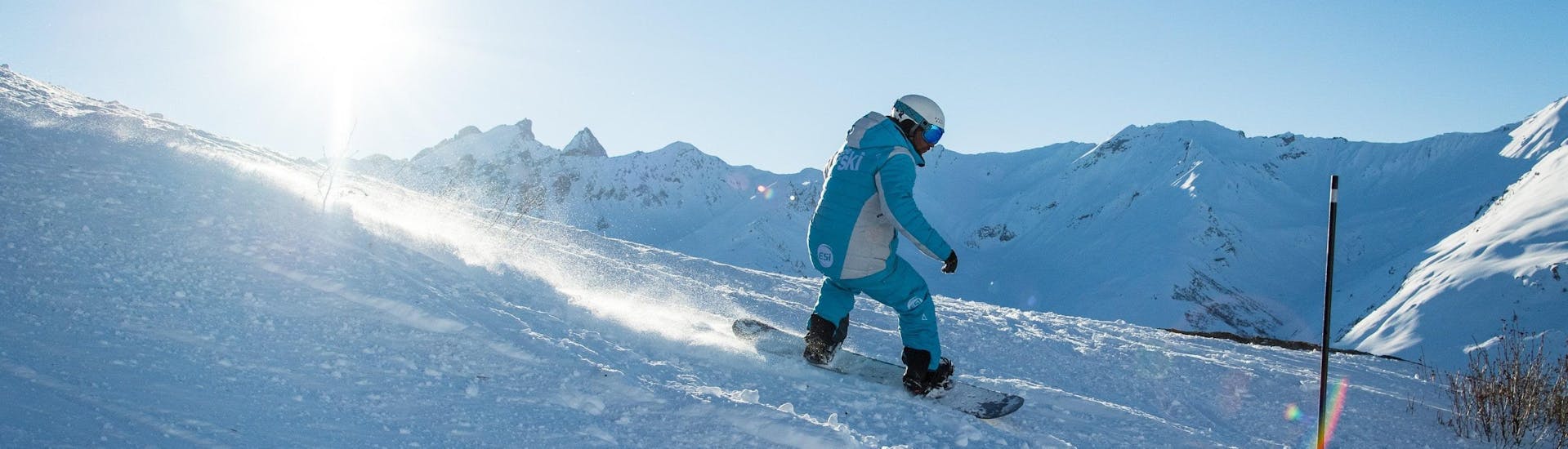 Un snowboardeur dévale une piste de poudreuse pendant son Cours particulier de snowboard avec l'école de ski ESI Dévoluy.