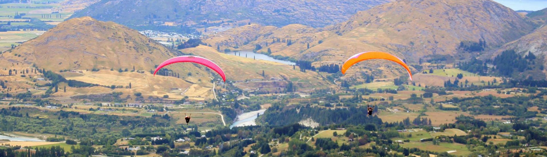 Two paragliders from Skytrek Queenstown are flying next to each other while Paragliding in Queenstown - Summer.