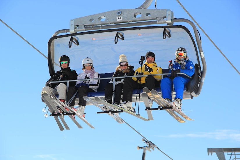 A group of friends is riding the ski lift during their Private Ski Lessons for Adults of All Levels with Skischule Habeler Mayrhofen.