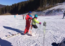 A young skier is having fun on the slopes with her ski instructor during the Private Ski Lessons for Kids - All Levels organized by the ski school Scuola di Sci Val Rendena in the ski resort of Pinzolo.