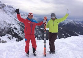 Ein Skilehrer der Skischule Scuola di Sci Val Rendena in Pinzolo lächelt bei der Aktivität Privater Skikurs für Erwachsene - Alle Levels gemeinsam mit seinem Schützling in die Kamera.