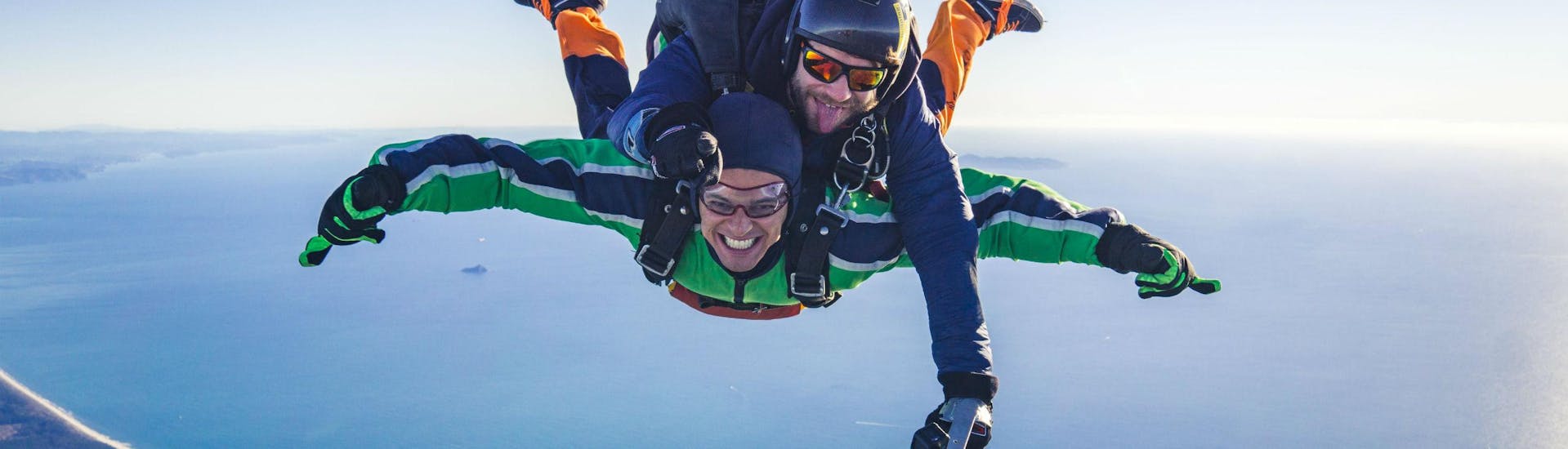 A tandem student is visibly enjoying himself while Tandem Skydiving in Tauranga with his tandem master from Skydive Tauranga.