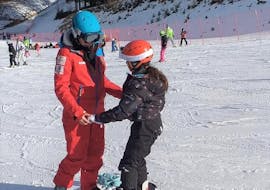 Een snowboardleraar leert de basis van snowboarden aan een jonge deelnemer van de snowboardlessen voor kinderen en volwassenen - eerste keer georganiseerd door de skischool Scuola di Sci Val Rendena in het skigebied van Pinzolo.