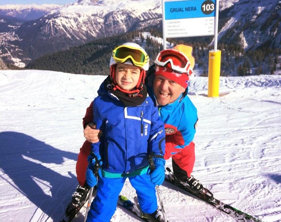 Skilessen voor kinderen (3-5 jaar) voor beginners met Scuola di Sci Val Rendena Een kind lacht naar de camera met zijn skileraar tijdens de kinderskilessen (3-5 j.) - eerste keer georganiseerd door de skischool Scuola di Sci Val Rendena in het skigebied van Pinzolo.