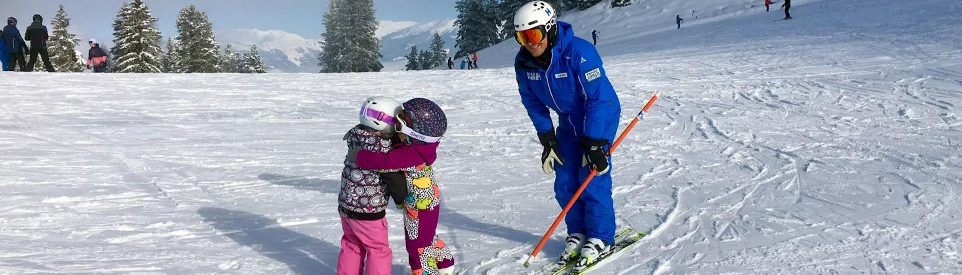 Dos niños pequeños se divierten durante sus clases particulares de esquí para niños (a partir de 3 años) de todos los niveles, mientras son supervisados ​​por su instructor de esquí de Skischule Habeler Mayrhofen.