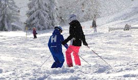 Ein Skilehrer der Skischule Habeler Mayrhofen zeigt einem Mädchen im m Kinder-Skikurs "MAX6" (ab 6 J.) für Anfänger die richtige Skitechnik.