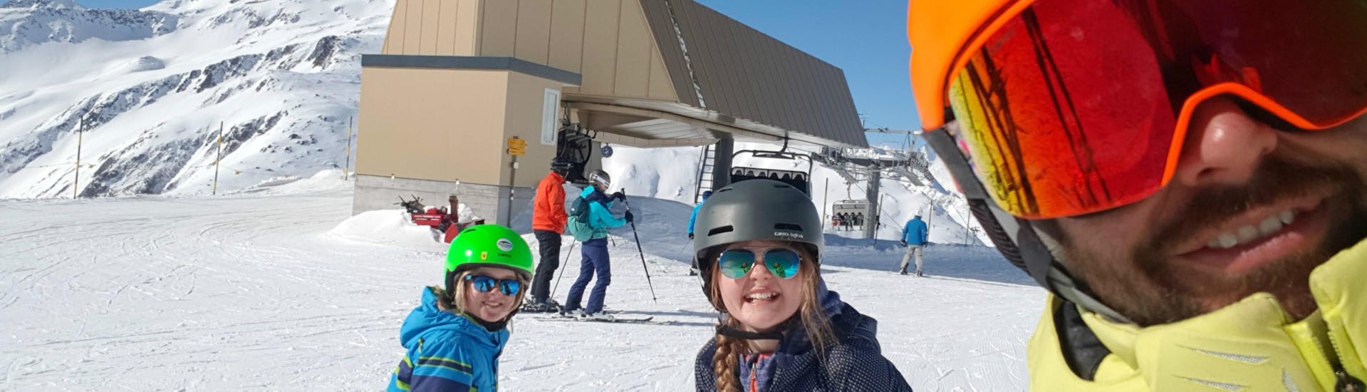 Two participants of the Kids Ski Lessons "Ils Camutschs" (4-17 years) are posing for a picture with their ski instructor from Skischule Monntains.