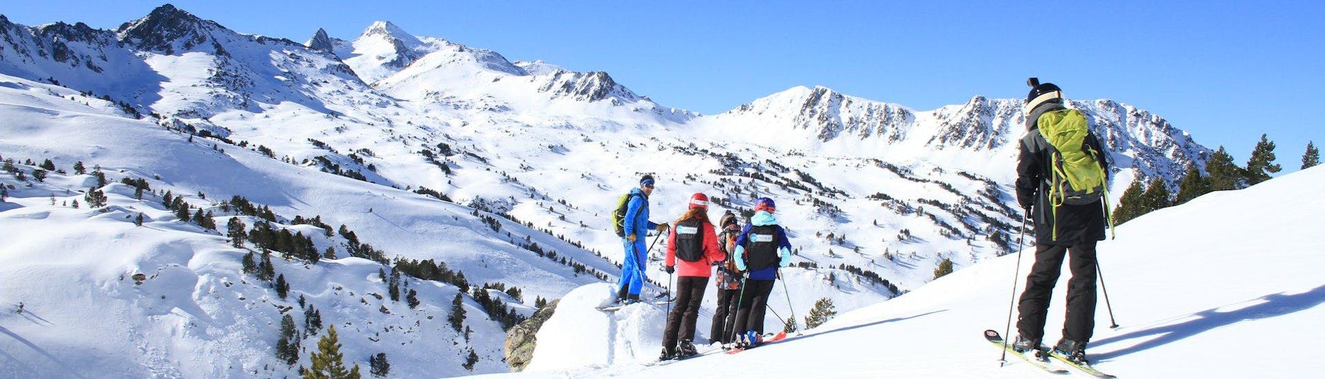 Unos esquiadores están parados justo debajo del telesilla y escuchando a su instructor de esquí antes del comienzo de sus clases de esquí para adultos - debutantes con la escuela de esquí ESI du Tourmalet. 