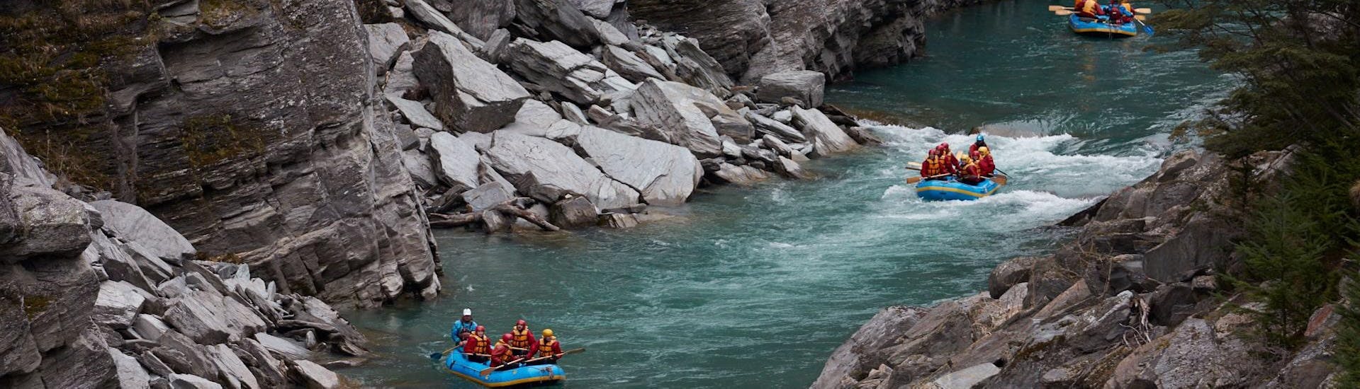 Participants of the White Water Rafting from Queenstown on Shotover River are observing rafts passing by with the local guides from Go Orange