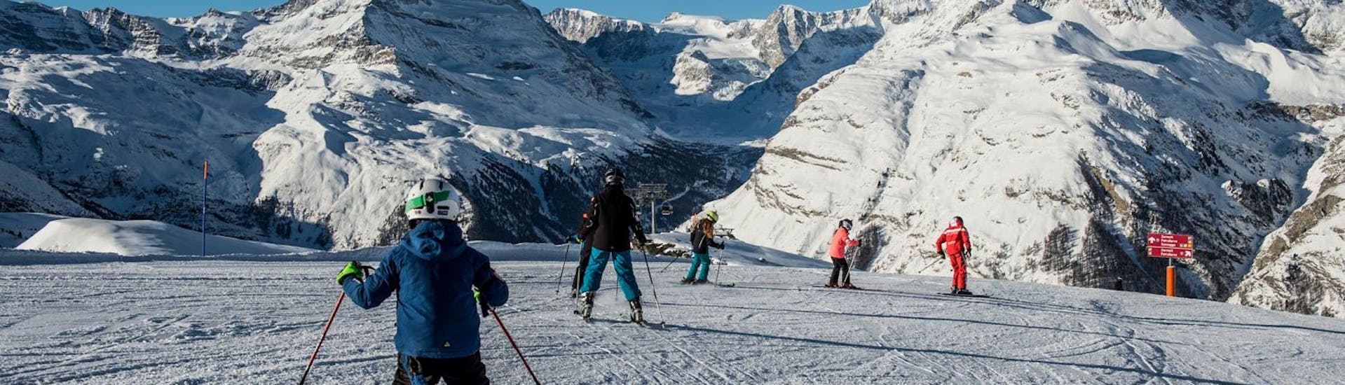 Les participants de Cours de Ski pour Enfants (6-14 ans) - Experimenté avec l'ecole de ski Zermatters suivent leurs moniteurs de ski sur les pistes de Matterhorn Ski Paradise.