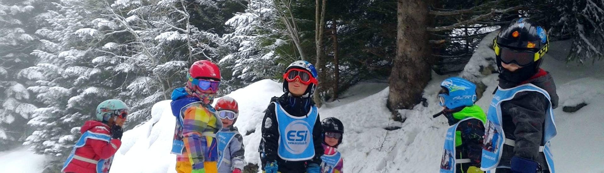 Des enfants se tiennent au milieu de la piste entourés d'arbres pendant leur Cours de ski pour Enfants (3-11 ans) - Vacances - Matin avec l'école de ski ESI Ecoloski Barèges.