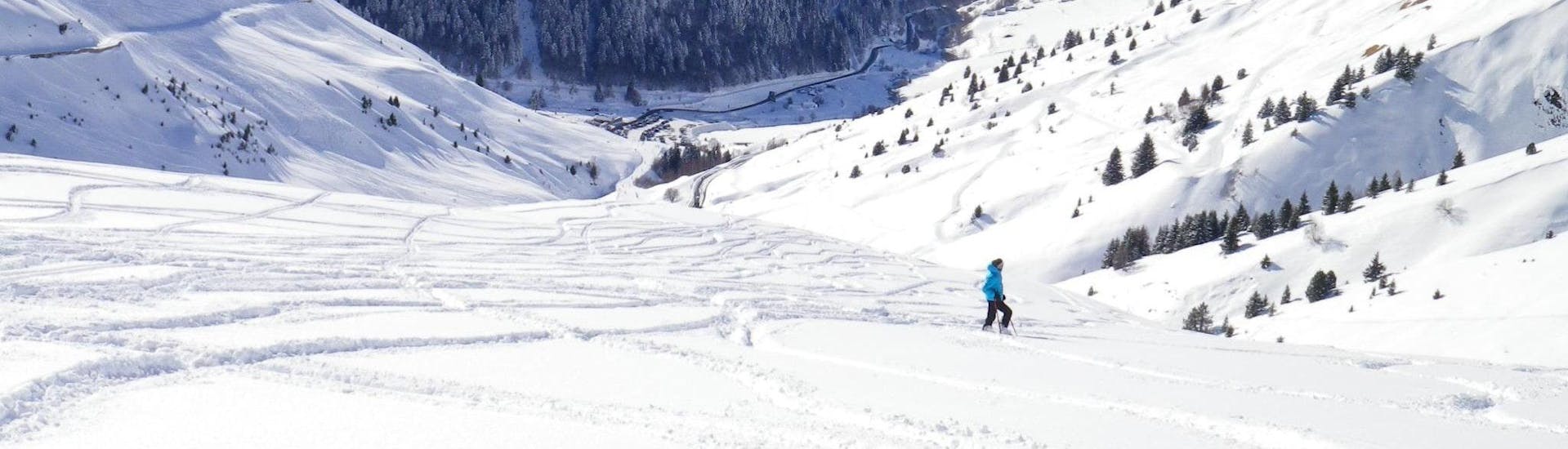 A ski instructor from the ski school ESI Ecoloski Barèges is standing in the middle of the beautiful mountain landscape of Le Grand Tourmalet where Ski Lessons for Adults - All Levels happen.