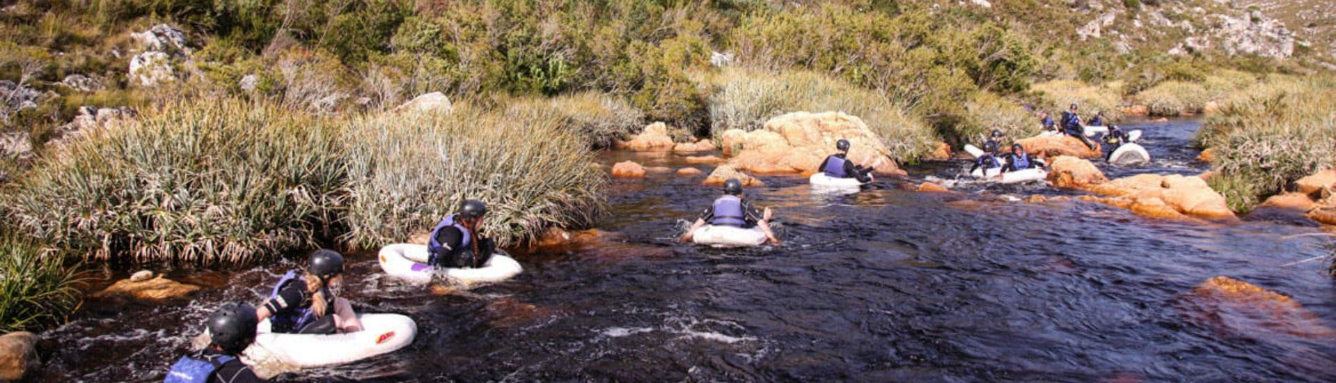 A group of people is being carried downstream while Tubing on Palmiet River in Kogelberg Nature Reserve with Gravity Adventures.