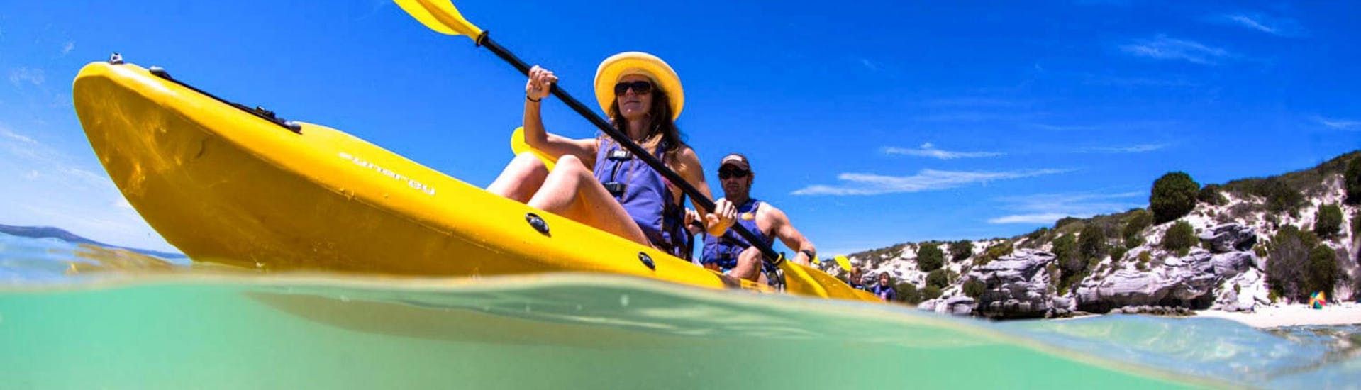 A couple is paddling across the turquoise waters of the Langebaan Lagoon while Sea Kayaking in West Coast National Park with Gravity Adventures.