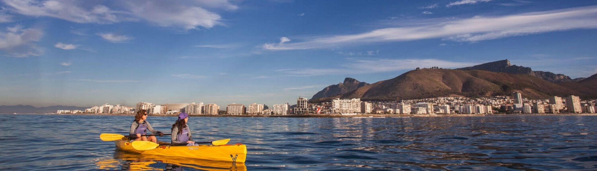 Two women are taking in the spectacular view of the city while Sea Kayaking in Cape Town with Gravity Adventures.