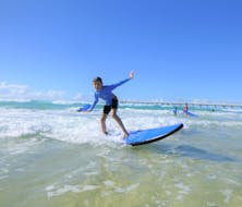 Een jonge surfer rijdt op een kleine golf tijdens de surflessen in gold coast voor kinderen georganiseerd door de surfschool Get Wet Surf School.