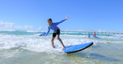 Surflessen in Gold Coast voor kinderen - Beginners met Get Wet Surf School Gold Coast Een jonge surfer rijdt op een kleine golf tijdens de surflessen in gold coast voor kinderen georganiseerd door de surfschool Get Wet Surf School.