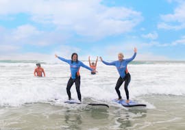 Two participants of the Surf Lessons in Gold Coast for Adults organized by the surf school Get Wet Surf School are having fun while riding a wave on the surfboard.