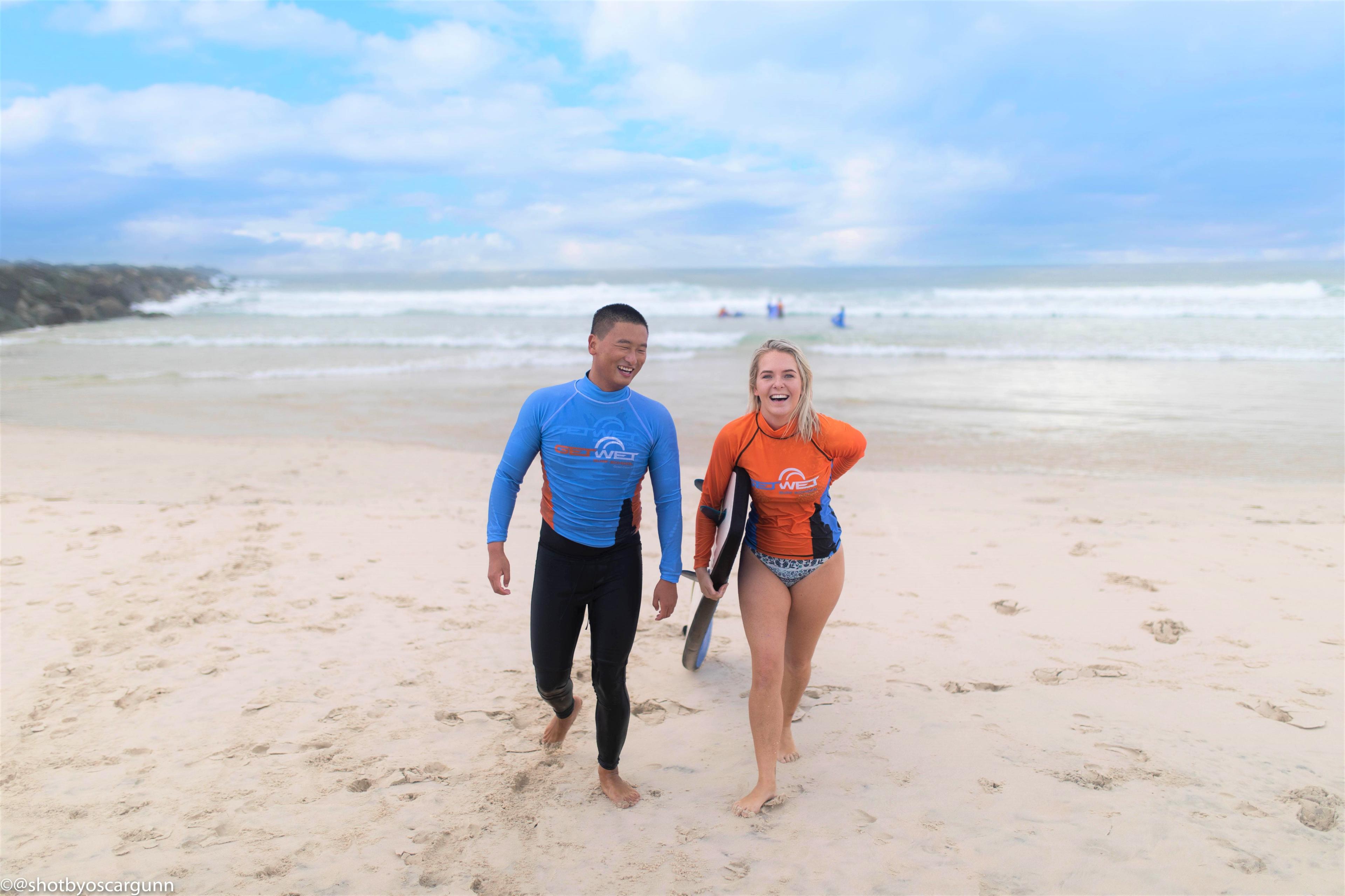 A participant of the Private Surf lessons in Gold Coast is having fun on the beach with his private instructor of the surf school Get Wet Surf School in Gold Beach.