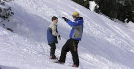 Foto van een instructeur en een deelnemer tijdens de Kids Snowboarding lessen "Learn 2 Ride" voor beginners met Snowboard School SMT Mayrhofen .